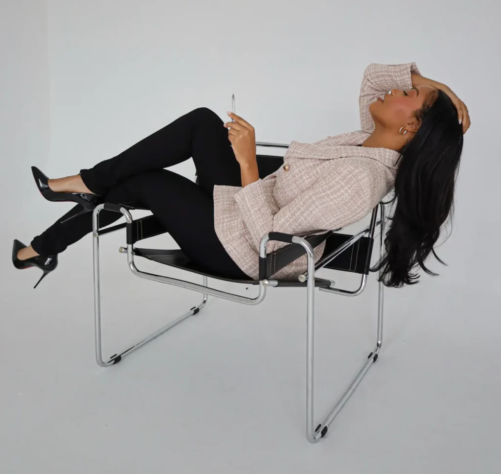 Person relaxing in designer chair, holding pen.