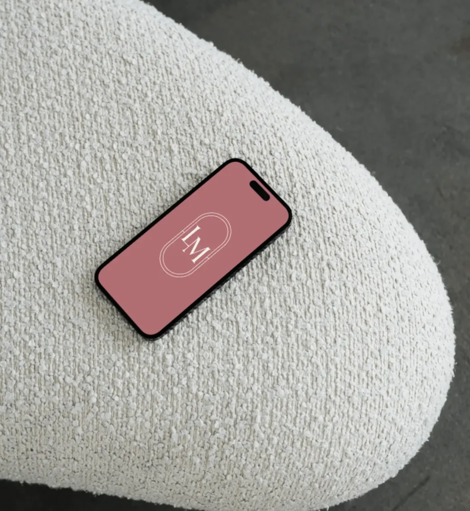 Smartphone on textured beige couch, logo on screen.