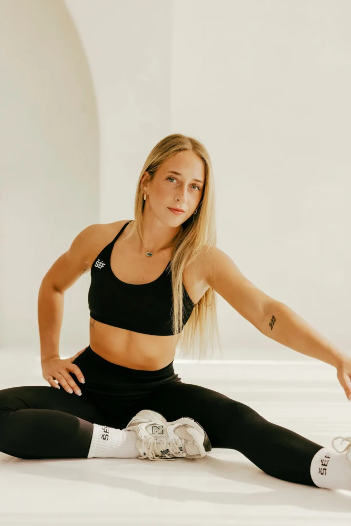 Woman stretching in athletic wear indoors.